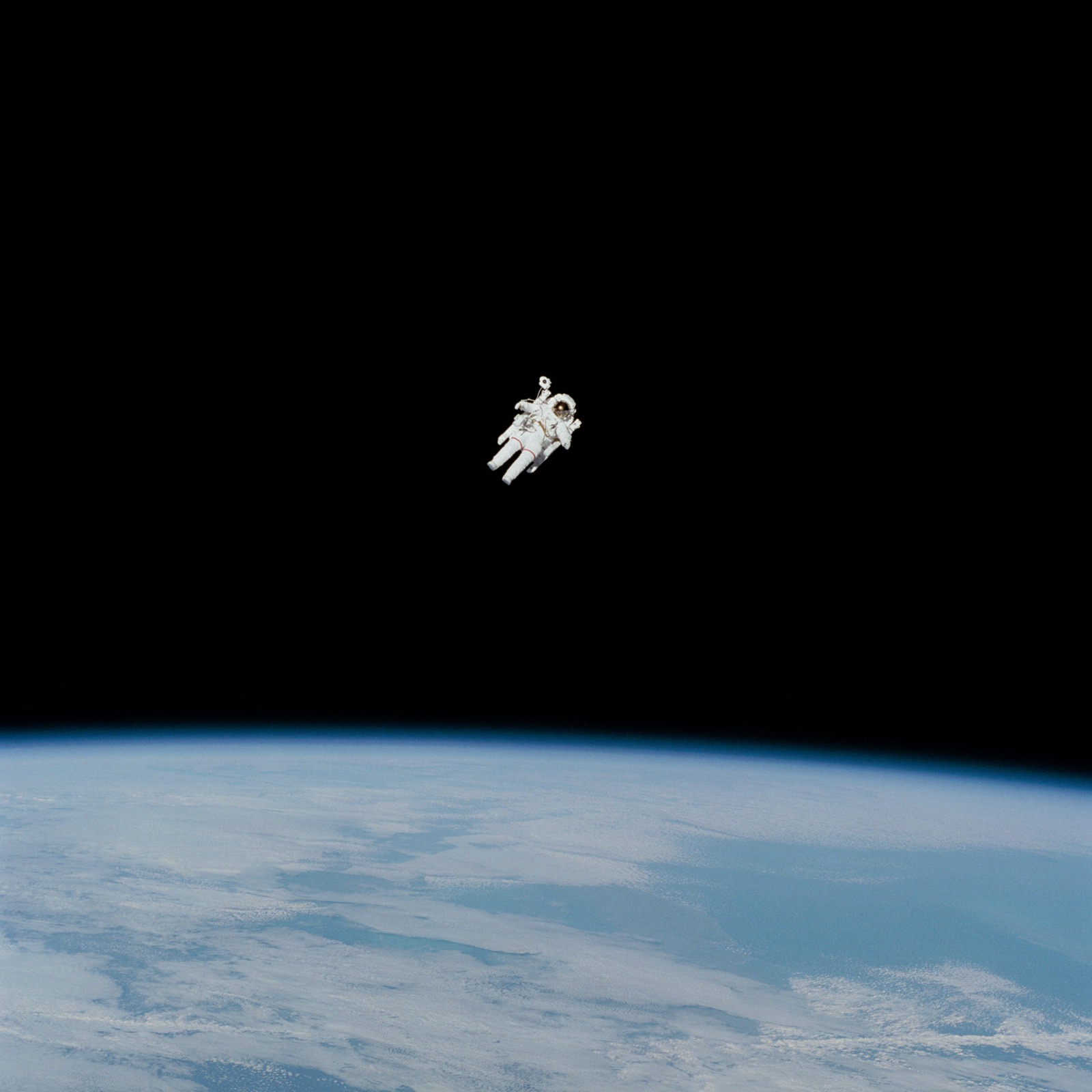 An astronaut works in orbit above a brilliant blue world